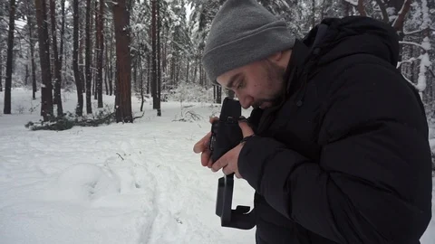 Photographer is standing in the deep snow in the winter forest and taking a shot 库存影片 101119985
