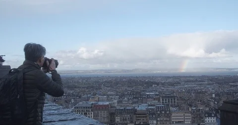 Photographer taking photo of Rainbow from top of Edinburgh castle in slow motion Stock Footage