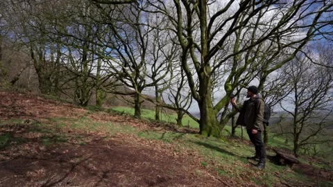 A photographer talking about his camera and walking through the woods 動画素材 239076039