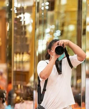 Photographer using camera to taking Self Portrait in the mirror.Photographe.. Stock Photos