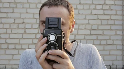 Photographer using a retro old camera. Brick wall in the background. Stock Footage 69825659