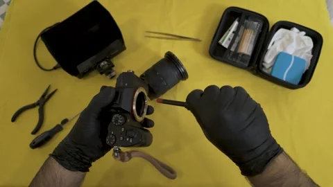 Photographer using a specialized brush on the camera body. Vidéo 327624201