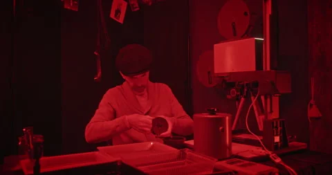 Photographer at Work in Darkroom Actively Processing Film Under Soft Red Light Video stock 305086098