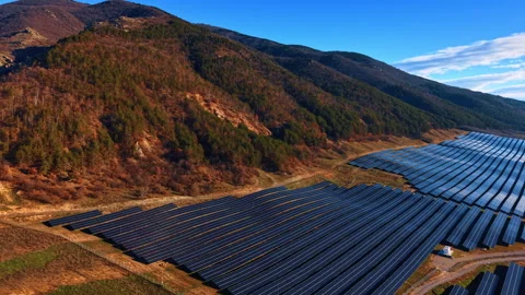 Photovoltaic solar array installation on sloping hills terrain. Aerial view of Stock Footage 330389813