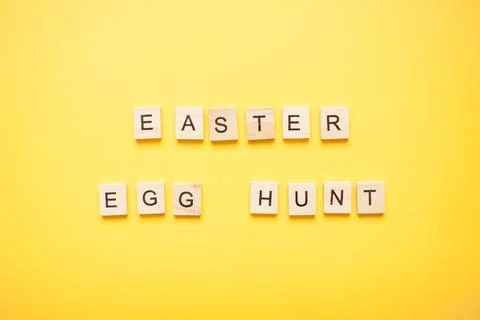 Phrase easter egg hunt made from wooden blocks on a light yellow background Stock Photos