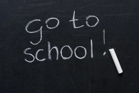Phrase go to school with exclamation mark and piece of chalk on blackboard Photos