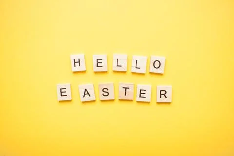 Phrase hello easter made from wooden blocks on a light yellow background Stock Photos