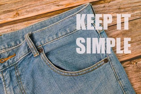 Phrase KEEP IT SIMPLE written on blue jeans and wooden background 写真素材