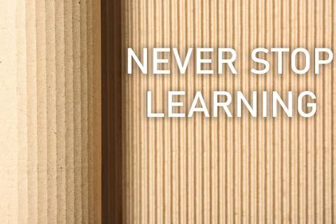 Phrase NEVER STOP LEARNING on corrugated cardboard, top view Foto stock