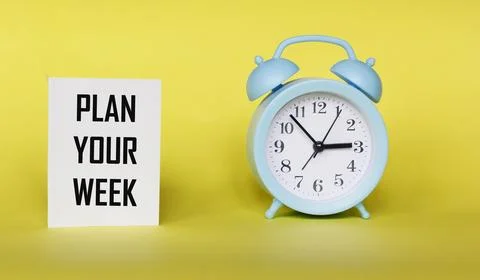 The phrase PLAN YOUR WEEK on a notepad and a yellow background with a clock Stock Photos