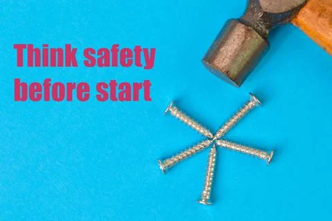 Phrase THINK SAFETY BEFORE STARTED written on a blue background with hammer a Foto stock