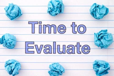 The phrase Time To Evaluate written on a lined notebook sheet with some crump Stock Photos