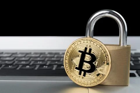 Physical bitcoin with padlock on a laptop computer keyboard. Stock Photos