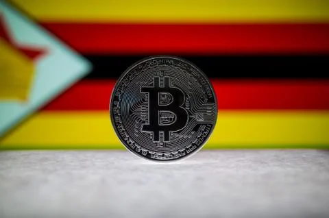 Physical silver version of Bitcoin BTC and Zimbabwe Flag on the background Stock Photos
