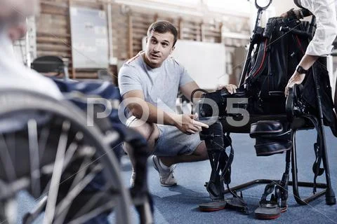 Physical therapist explaining equipment to man in wheelchair Stock Photos