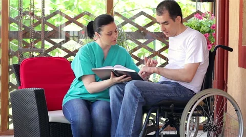 Physical therapist explaining exercises to young man in wheelchair Stock Footage 50646277