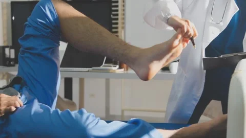 Physical therapist performing ankle examination on patient in clinic Stock Footage 343708115
