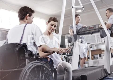 Physical therapist showing digital tablet to man in wheelchair Stock Photos
