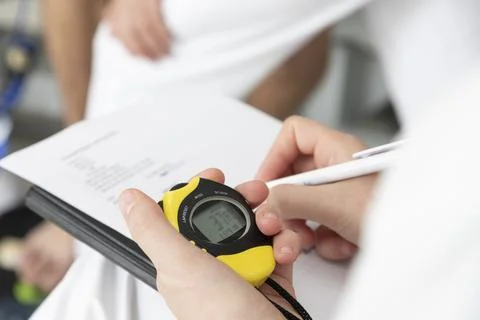 A physical trainer times a physical test, a stopwatch in hand Stock Photos