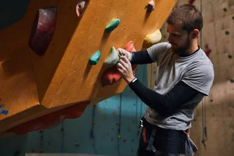 Physically challenged boulderer fixing artificial rocks and holds at climbing Stock Photos