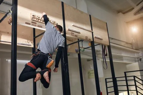 Physically challenged climber performing special exercises at wooden panel Stock Photos