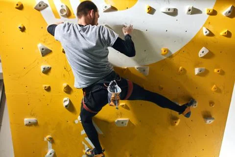 Physically challenged climber training hard, climbing up at yellow rock wall Stock Photos