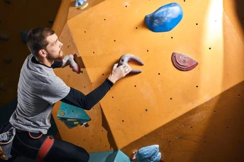 Physically challenged man climbing on artificial colourful rock wall Stock Photos