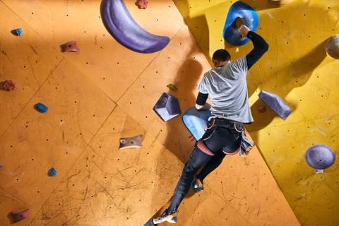 Physically challenged man climbing wall with colorful holds and rocks Stock Photos
