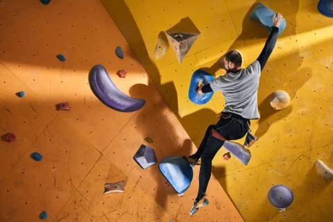 Physically challenged man stuck at difficult rock wall in bouldering gym Stock Photos