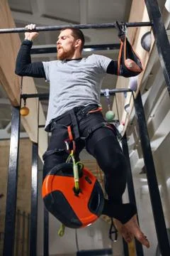 Physically challenged young man doing pull up exercises with heavy load Stock Photos