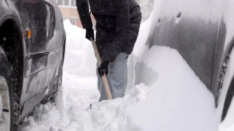 Physically demanding task of removing hardened snow from narrow parking gap Stock Footage 327894595