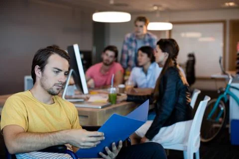 Physically disabled man on wheelchair reading a file in office Stock Photos