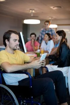 Physically disabled man on wheelchair using tablet in office Stock Photos