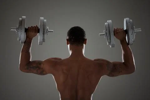 Physically fit man lifting dumbbells Stock Photos