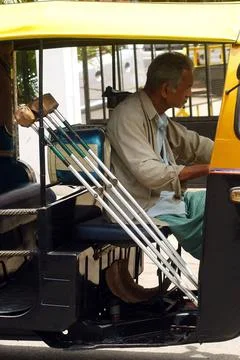 A physically handicapped rickshaw driver drives a auto rickshaw in Bangalo... Stock Photos