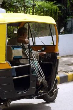 A physically handicapped rickshaw driver drives a auto rickshaw in Bangalo... Stock Photos