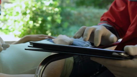 Physician doing CPR to female lying on stretcher, medic typing data on tablet Stock Footage 95862682