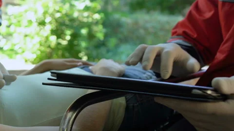 Physician doing CPR to female lying on stretcher, medic typing data on tablet Stock Footage 95864354