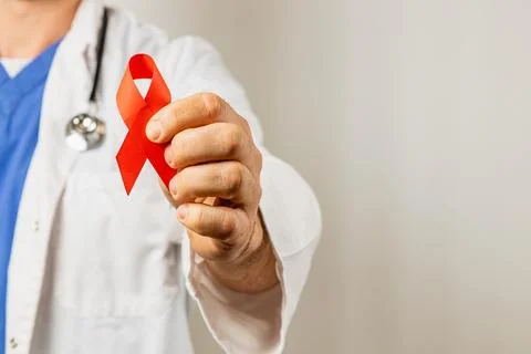 Physician holds red ribbon symbolizing support for HIV awareness campaign Stock Photos