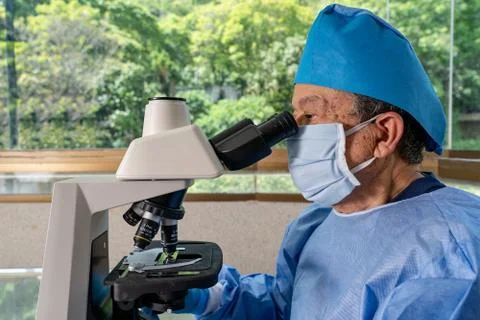 Physician looking through microscope Stock-Fotos