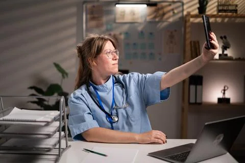Physician nurse using smartphone taking selfie working over hours in hospital Stock Photos