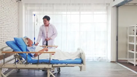 Physician performs checkup on elderly patient in hospital bed. Bright ward Stock Footage 317256447