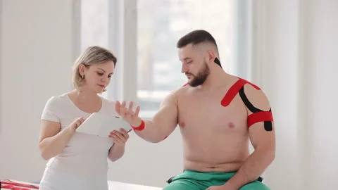 The physiologist laughs and talking with the patient, her using digital tablet Stock Footage 130217750