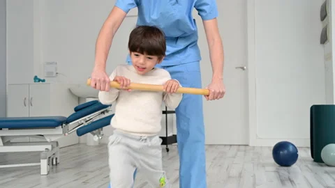 Physiotherapist and kid walking in rehabilitation center. Doctor supports a Stock Footage