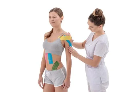 Physiotherapist applying kinesio tape on female patients shoulder Stock Photos