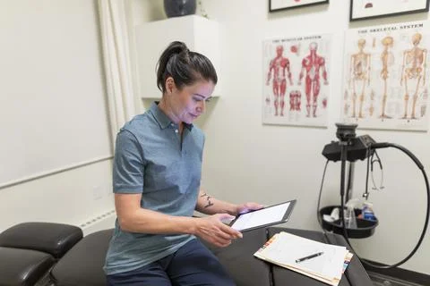 Physiotherapist doing paperwork with digital tablet Stock Photos