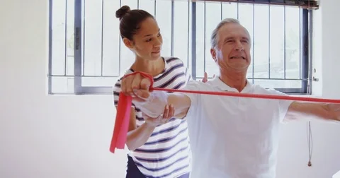 Physiotherapist helping patient in performing exercise with resistance band 4k Video stock 81099231