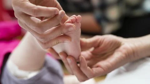 A physiotherapist manually treats an infant's foot Stock Photos