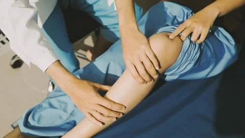 Physiotherapist performing a knee exercise for a patient Stock Footage 325966714