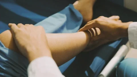 Physiotherapist performing a knee exercise for a patient Stock Footage 325966733
